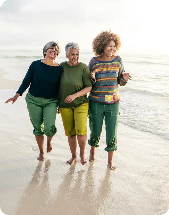 Three women laughing by the ocean