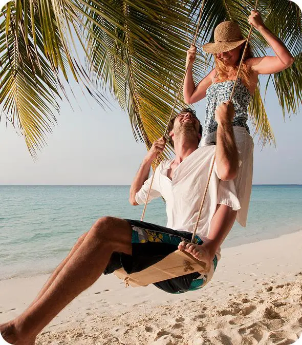 Couple swinging under palm on beach